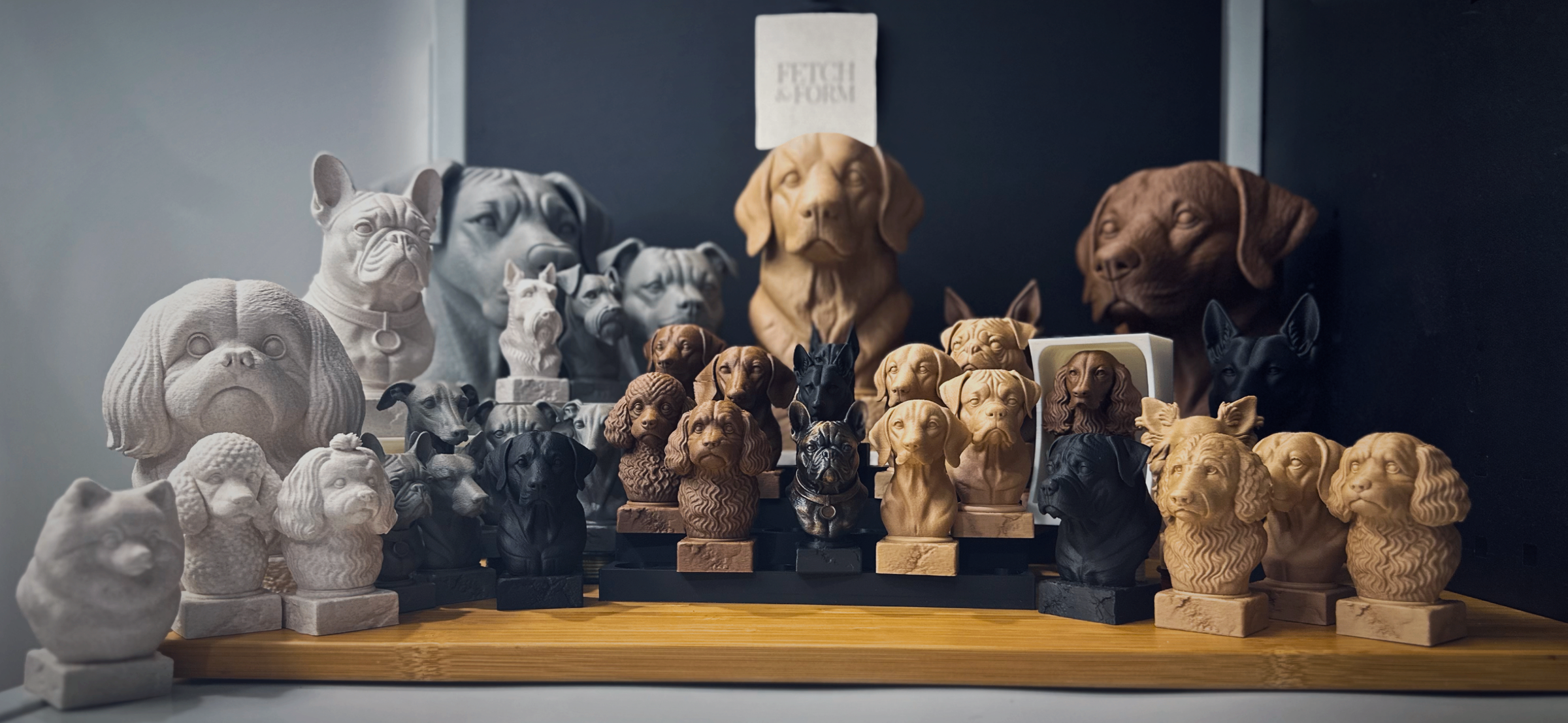 Collection of 3D Printed dog-themed sculptures on a wooden shelf against a dark wall.