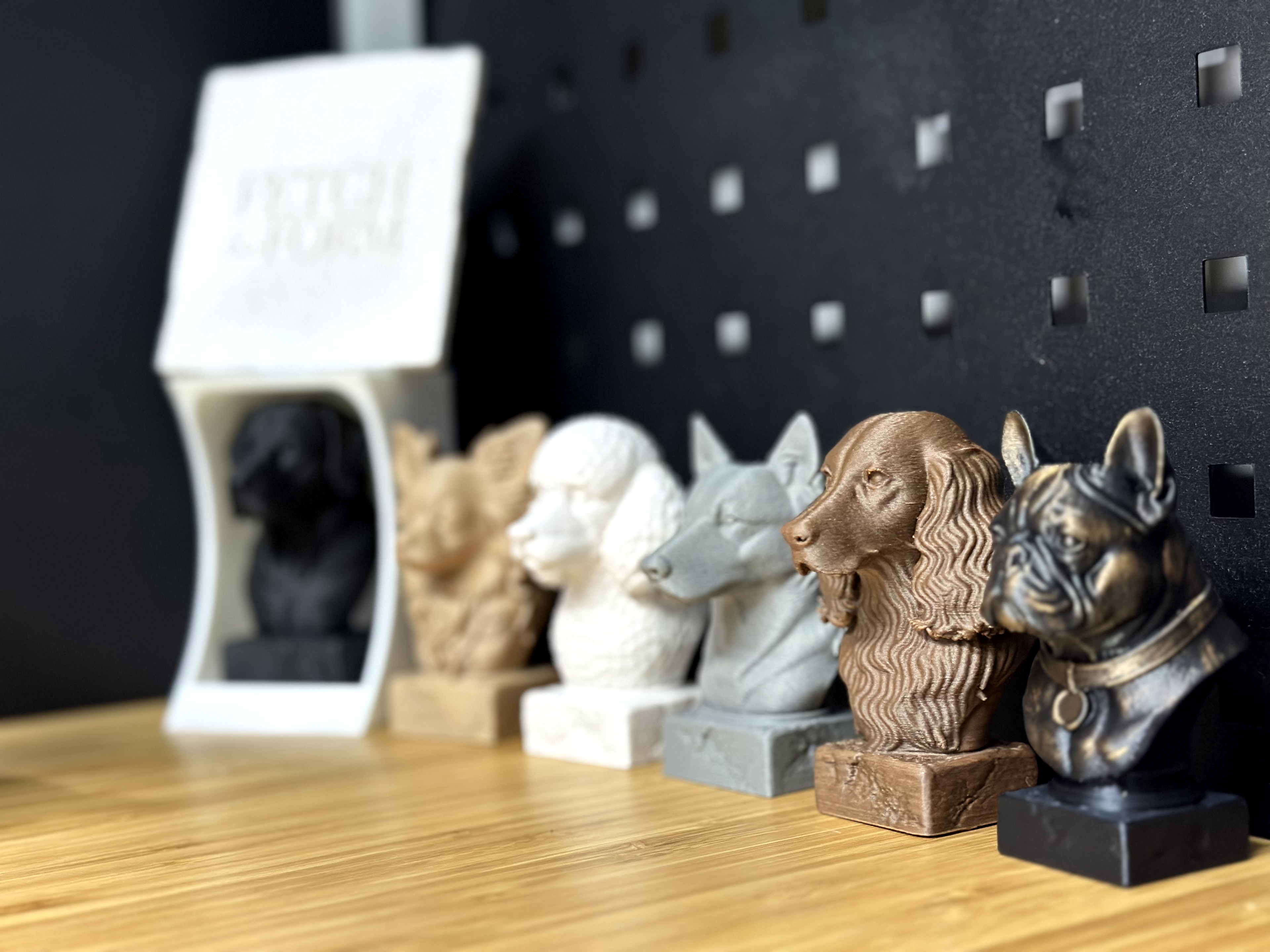 Collection of 3D Printed Dog Busts on a wooden surface with a pegboard background